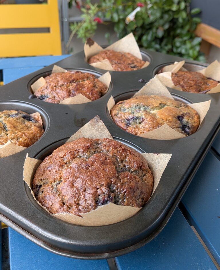 Blueberry Muffins Recipe – Method 1: Made with Oil, Freshly baked blueberry muffins made with oil, golden tops, vibrant bursts of blueberries, soft fluffy texture, muffins cooling on a rack, natural light, home-baked breakfast treat, saru's diary, saru's not so secret diary, easy muffin recipes, muffins, blueberries recipe, food recipes, dessert recipes, baking recipes