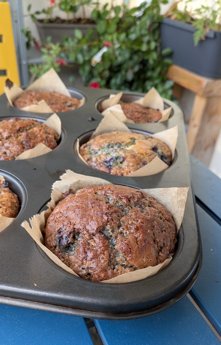 Blueberry Muffins Recipe – Method 1: Made with Oil, Freshly baked blueberry muffins made with oil, golden tops, vibrant bursts of blueberries, soft fluffy texture, muffins cooling on a rack, natural light, home-baked breakfast treat, saru's diary, saru's not so secret diary, easy muffin recipes, muffins, blueberries recipe, food recipes, dessert recipes, baking recipes