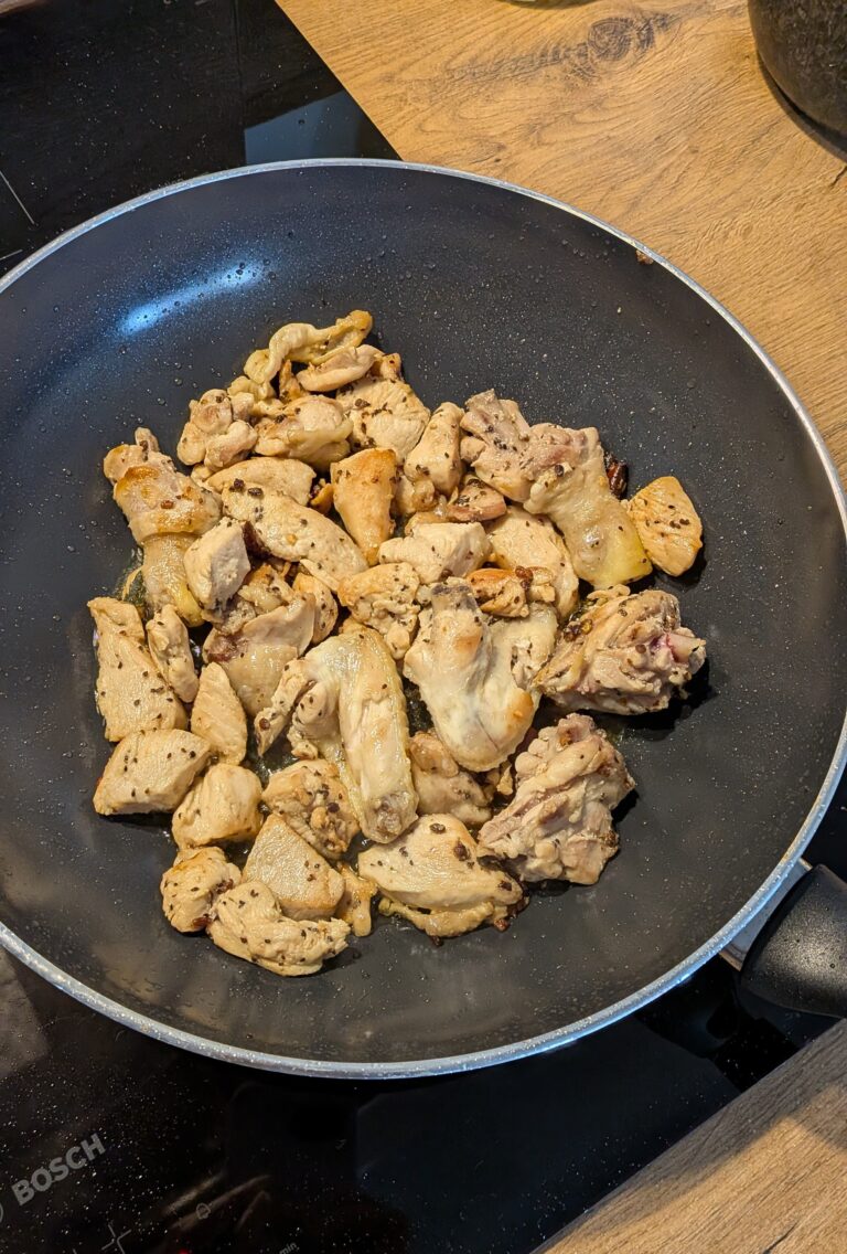 Nepali chicken curry in a traditional bowl with fresh cilantro and scallion garnish, Close-up of bone-in chicken pieces in thick tomato gravy, Step-by-step frying chicken in a heavy-bottomed pan with spices, Grinding ginger-garlic with powdered spices in a mortar and pestle, Adding tomatoes and ground spices to the chicken curry, Finished Nepali chicken curry served with steamed rice and roti, Garnishing chicken curry with fresh cilantro and scallions, Nepali Chicken Curry (Kukhura Ko Masu) – A Home-Style Recipe From My Roots, saru's diary, saru's not so secret diary, nepali food , nepali food blog, food around the world, chicken recipes around the world