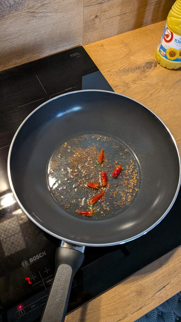 Nepali chicken curry in a traditional bowl with fresh cilantro and scallion garnish, Close-up of bone-in chicken pieces in thick tomato gravy, Step-by-step frying chicken in a heavy-bottomed pan with spices, Grinding ginger-garlic with powdered spices in a mortar and pestle, Adding tomatoes and ground spices to the chicken curry, Finished Nepali chicken curry served with steamed rice and roti, Garnishing chicken curry with fresh cilantro and scallions, Nepali Chicken Curry (Kukhura Ko Masu) – A Home-Style Recipe From My Roots, saru's diary, saru's not so secret diary, nepali food , nepali food blog, food around the world, chicken recipes around the world