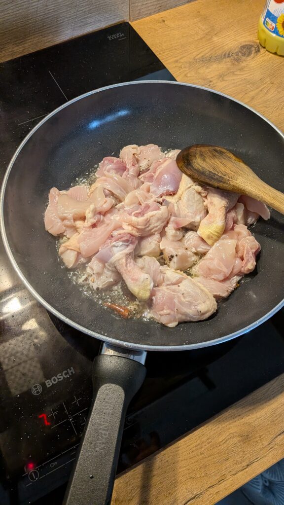 Nepali chicken curry in a traditional bowl with fresh cilantro and scallion garnish, Close-up of bone-in chicken pieces in thick tomato gravy, Step-by-step frying chicken in a heavy-bottomed pan with spices, Grinding ginger-garlic with powdered spices in a mortar and pestle, Adding tomatoes and ground spices to the chicken curry, Finished Nepali chicken curry served with steamed rice and roti, Garnishing chicken curry with fresh cilantro and scallions, Nepali Chicken Curry (Kukhura Ko Masu) – A Home-Style Recipe From My Roots, saru's diary, saru's not so secret diary, nepali food , nepali food blog, food around the world, chicken recipes around the world