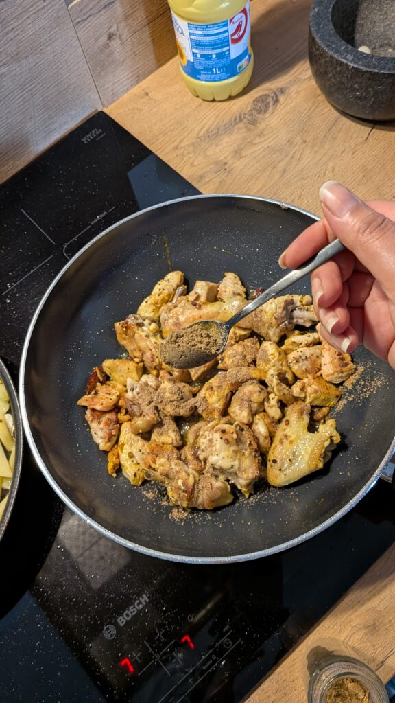 Nepali chicken curry in a traditional bowl with fresh cilantro and scallion garnish, Close-up of bone-in chicken pieces in thick tomato gravy, Step-by-step frying chicken in a heavy-bottomed pan with spices, Grinding ginger-garlic with powdered spices in a mortar and pestle, Adding tomatoes and ground spices to the chicken curry, Finished Nepali chicken curry served with steamed rice and roti, Garnishing chicken curry with fresh cilantro and scallions, Nepali Chicken Curry (Kukhura Ko Masu) – A Home-Style Recipe From My Roots, saru's diary, saru's not so secret diary, nepali food , nepali food blog, food around the world, chicken recipes around the world
