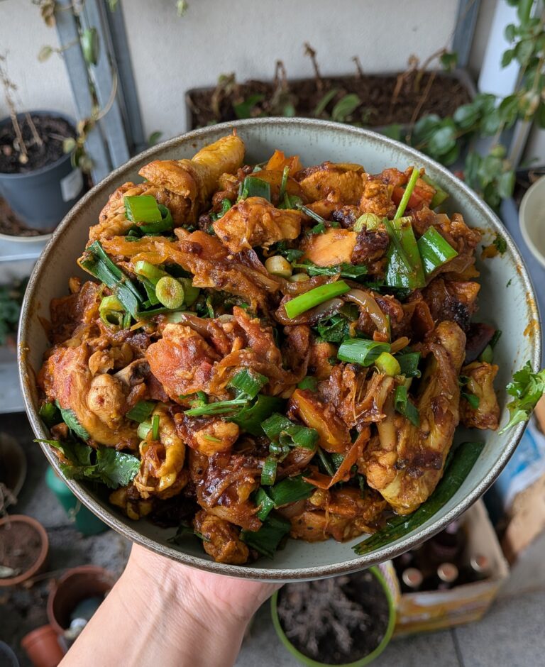 Nepali chicken curry in a traditional bowl with fresh cilantro and scallion garnish, Close-up of bone-in chicken pieces in thick tomato gravy, Step-by-step frying chicken in a heavy-bottomed pan with spices, Grinding ginger-garlic with powdered spices in a mortar and pestle, Adding tomatoes and ground spices to the chicken curry, Finished Nepali chicken curry served with steamed rice and roti, Garnishing chicken curry with fresh cilantro and scallions, Nepali Chicken Curry (Kukhura Ko Masu) – A Home-Style Recipe From My Roots, saru's diary, saru's not so secret diary, nepali food , nepali food blog, food around the world, chicken recipes around the world